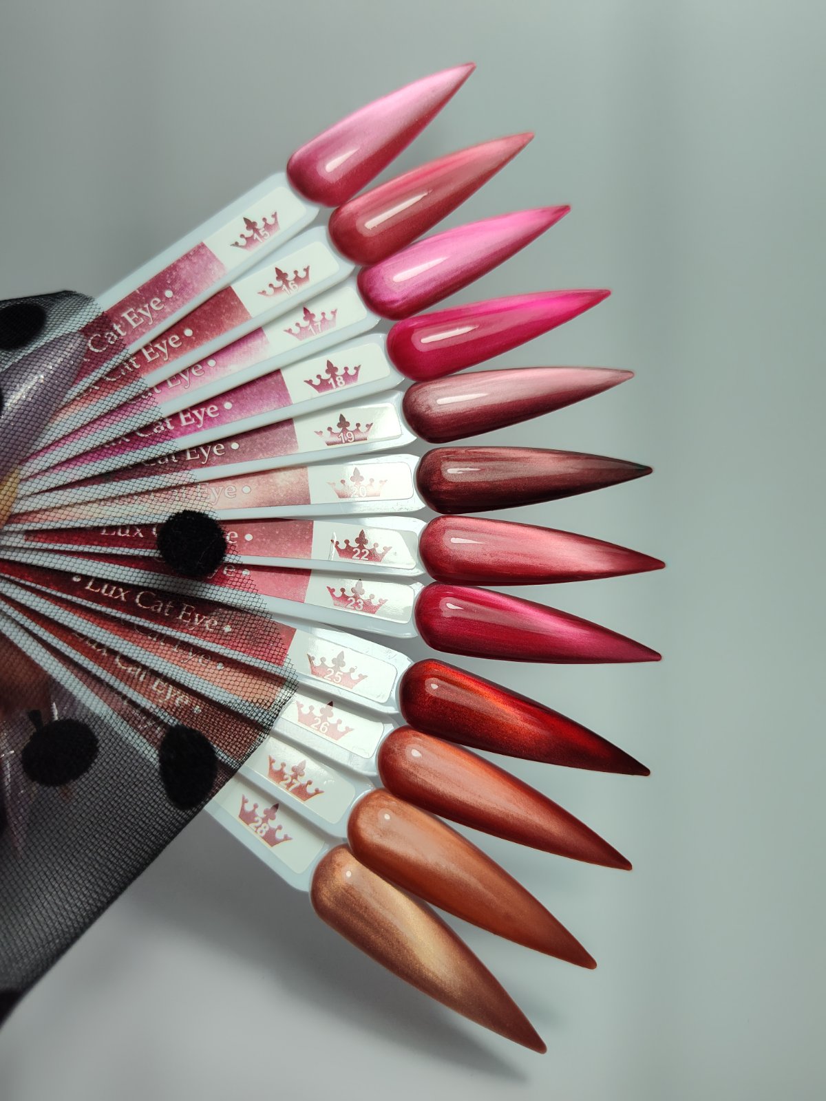 Гел лак Lux Cat Eye - 15 в червено-розови и медно-кафяви нюанси, с ефект на котешко око, показан на мостри за нокти.